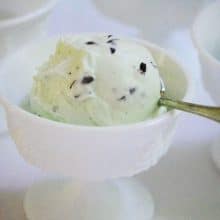 Mint chocolate chip ice cream in a white cup with spoon