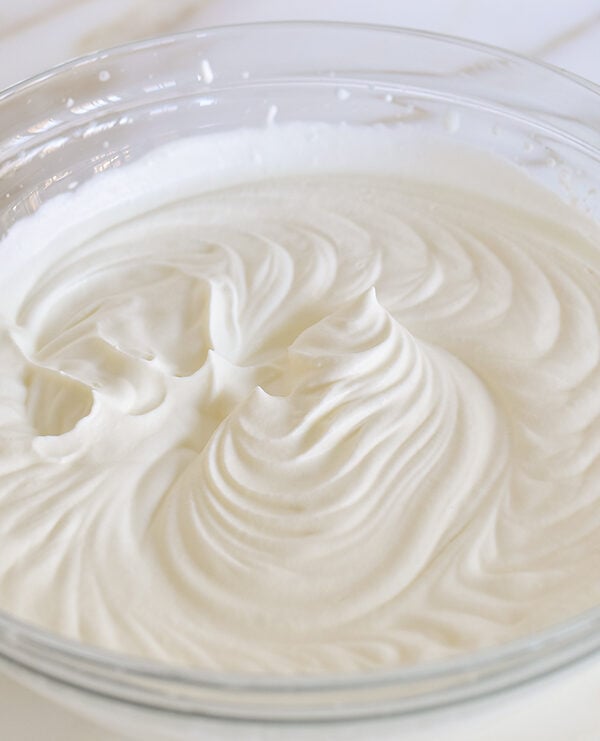 Whipped cream in a glass bowl on a marble counter