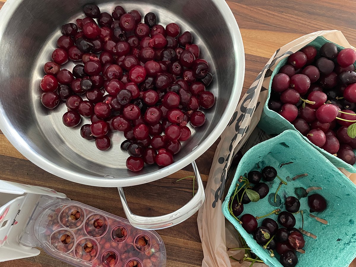 cherries in a pot with a pitter on the side
