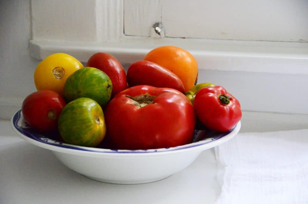 Bowl of red, yellow, and green tomatoes on the white kitchen counter, Maureen Abood