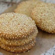 Cookies coated with sesame seeds in a stack on parchment paper
