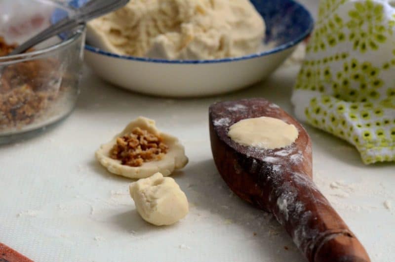 Maamoul cookie dough fitted into the wooden mold with a bowl of cookie dough in the background.