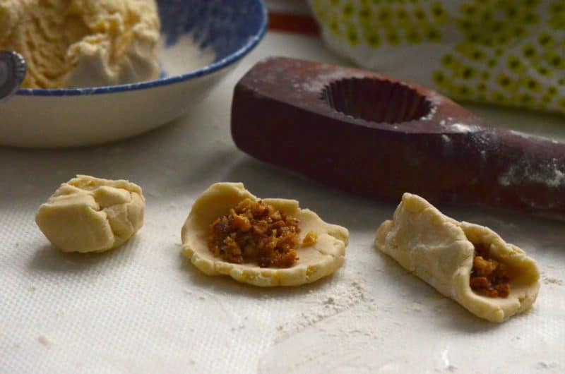 Maamoul cookie dough being stuffed with walnut filling.