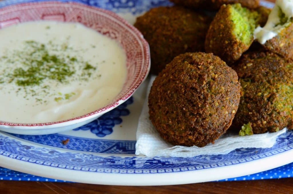 Homemade Fresh Herb Falafel is ready to eat with tahini yogurt sauce, on a lovely blue plate.