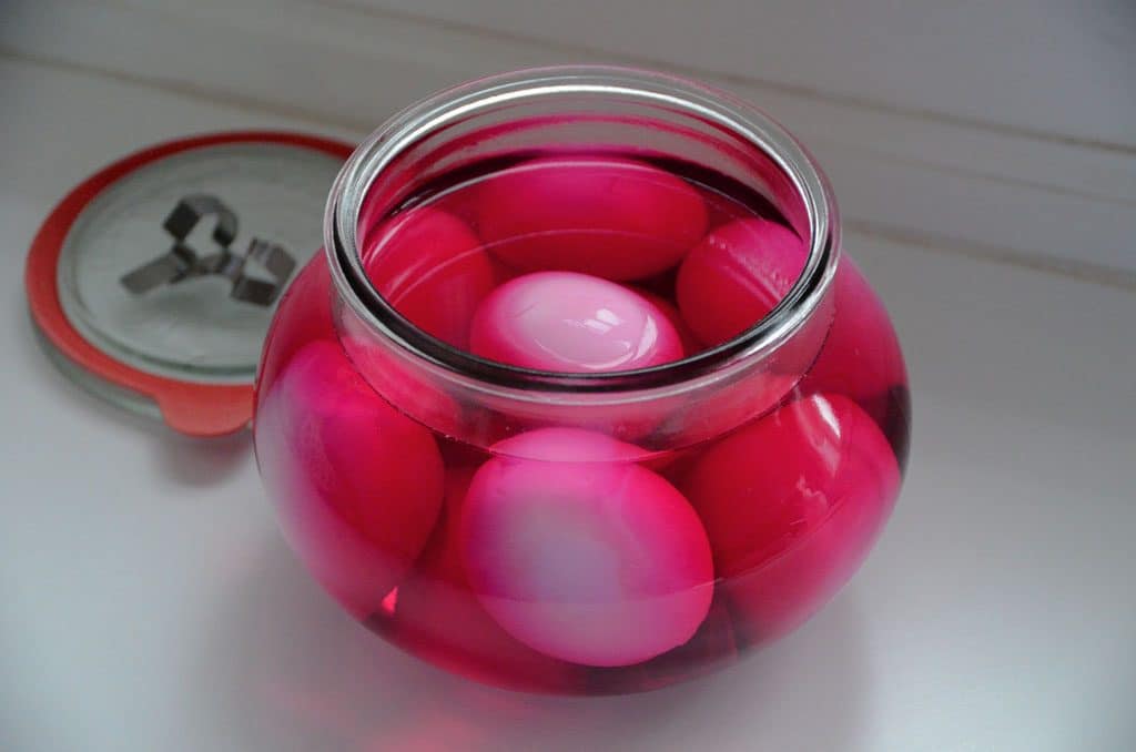 Pink pickled eggs in a glass jar.