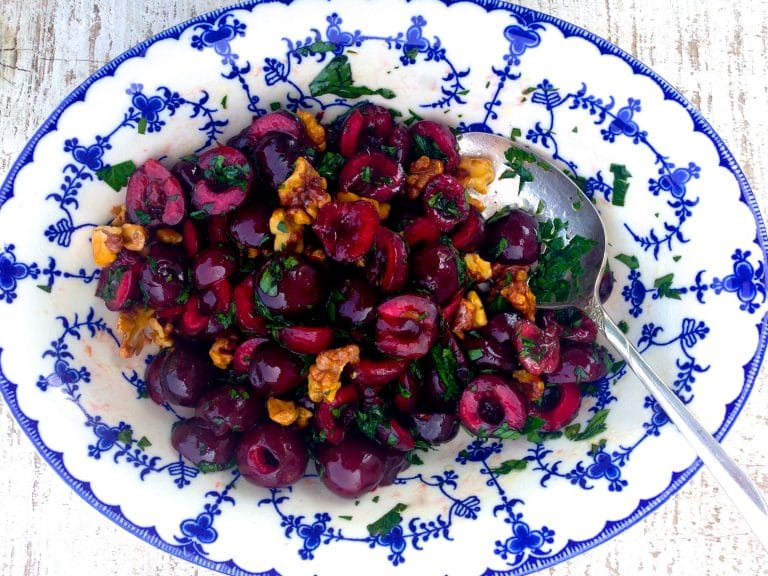 Cherry and walnut salad with green parsley in a blue and white bowl