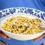 Grilled yellow corn salad with herbs and feta in a blue rimmed bowl