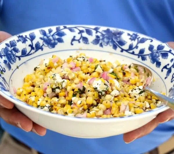 Grilled yellow corn salad with herbs and feta in a blue rimmed bowl