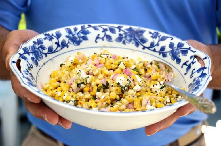 Grilled yellow corn salad with herbs and feta in a blue rimmed bowl