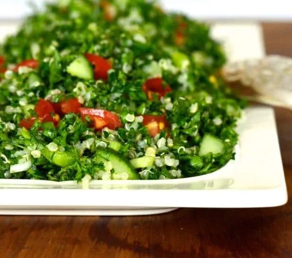 Bright green Quinoa Tabbouleh on a white rectangular platter