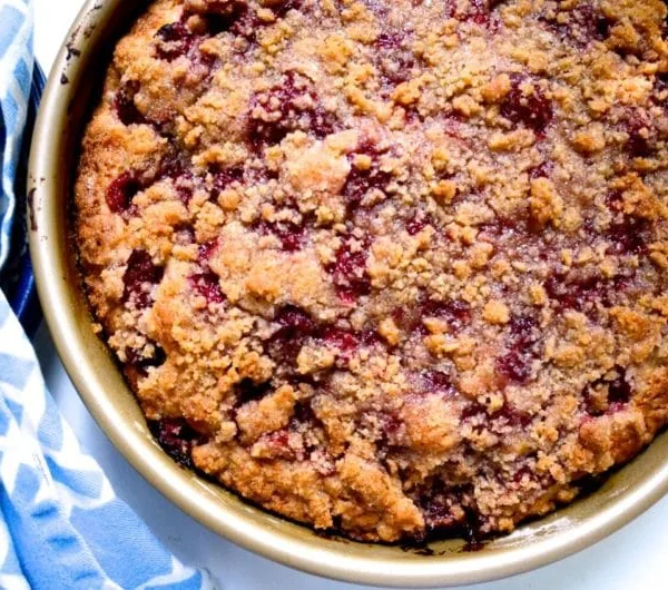 Top view of raspberry crumbcake in a round pan with blue napkin