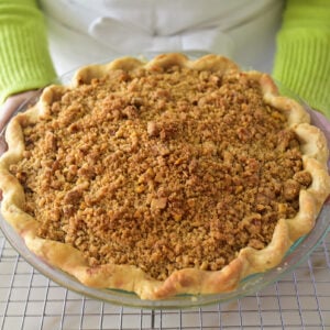 Dutch Apple pie held by two hands with green sleeves