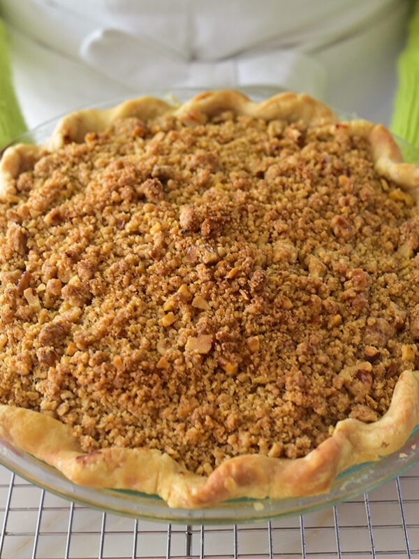 Dutch Apple pie held by two hands with green sleeves