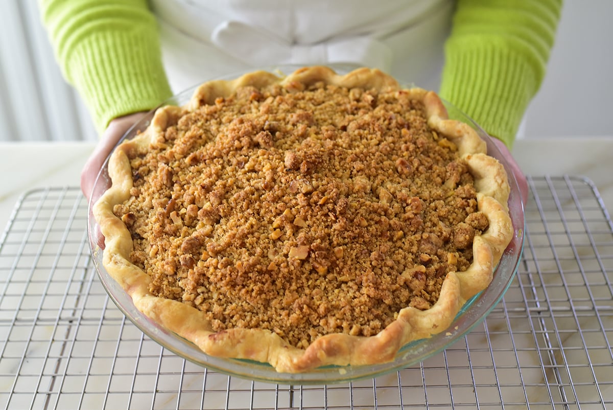 Dutch apple pie held by arms with green sleeves