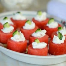 Small watermelon discs topped with labneh and mint on an oval white dish