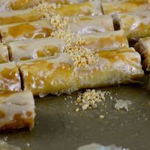 Almond baklawa fingers in a pan, cut in pieces with crushed almonds on top
