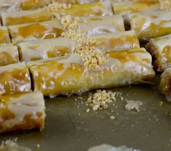 Almond baklawa fingers in a pan, cut in pieces with crushed almonds on top