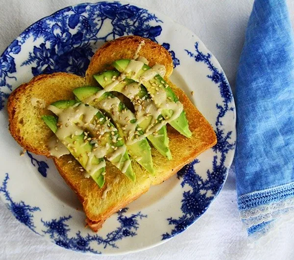 Salted Tahini Avocado Toast on a blue floral plate with blue linen napkin.