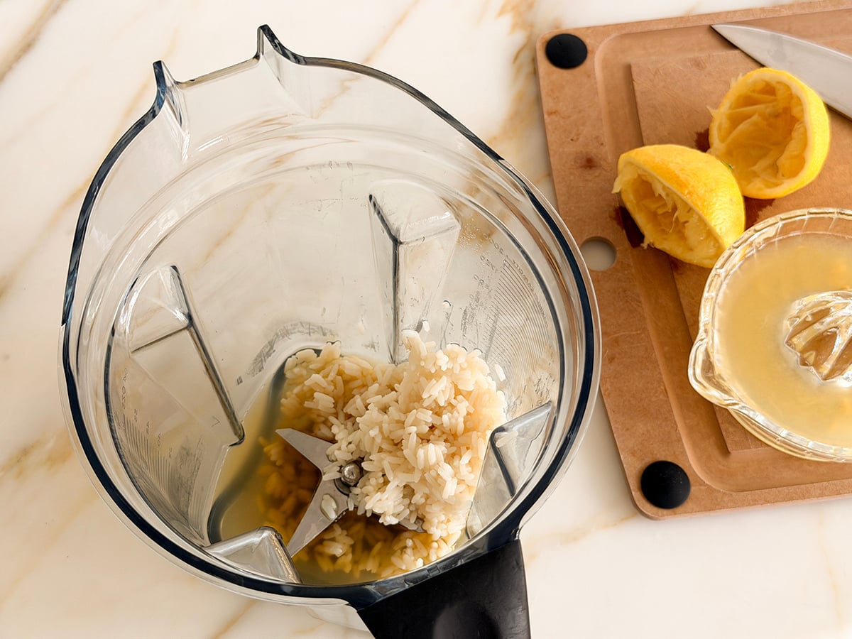 Rice and chicken stock in a blender with lemons on the side