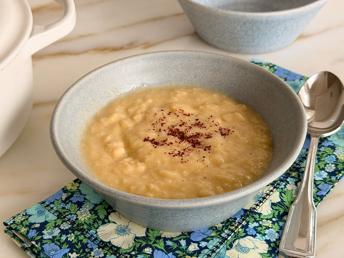 Avgolemono soup in a blue bowl with floral napkin