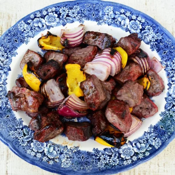 Lamb Shish Kebab with onions and peppers on a blue platter