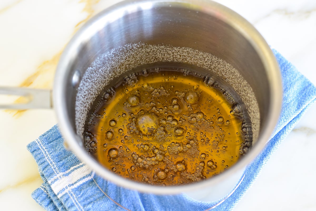 Sugar and water caramelized in a pot set on a blue towel