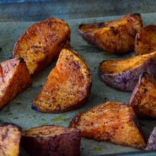 Sweet potato wedges with red sumac on top on a sheet pan