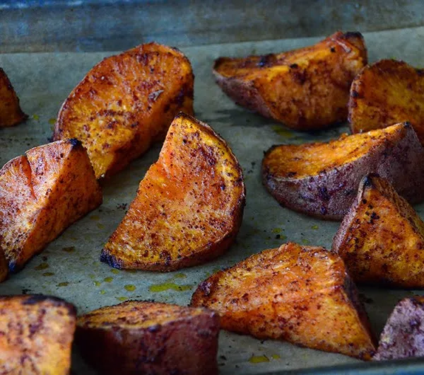 Sweet potato wedges with red sumac on top on a sheet pan
