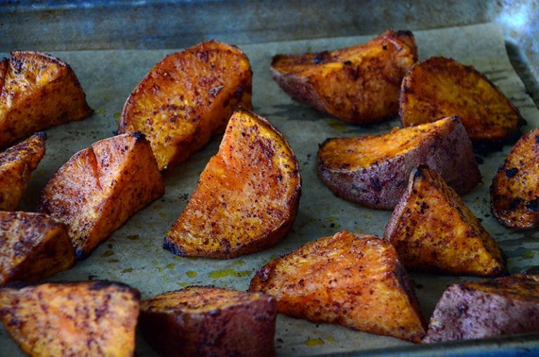 Sweet potato wedges with red sumac on top on a sheet pan
