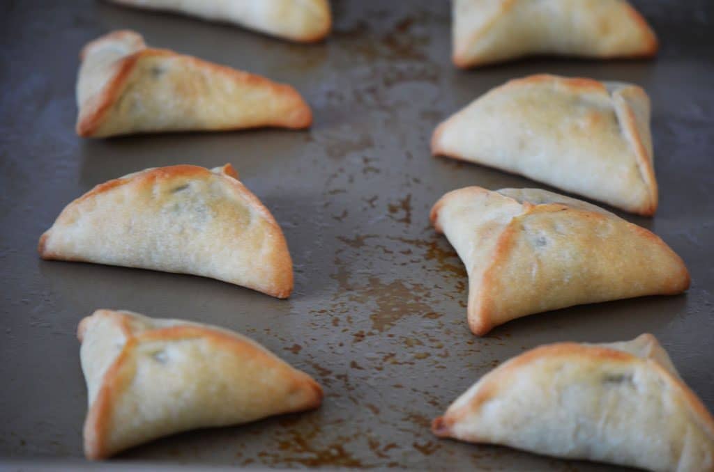 Fatayer Lebanese triangle shaped pies on a sheet pan