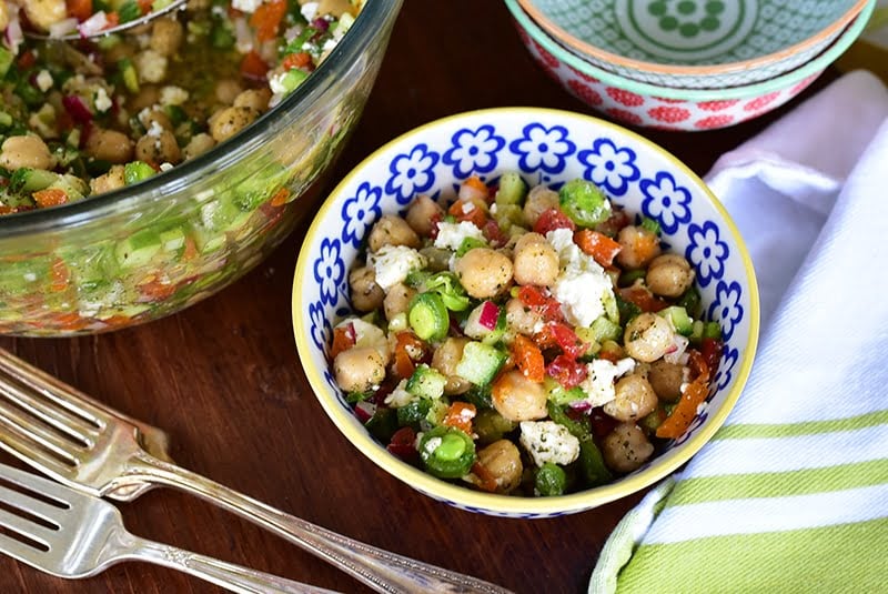 Chickpea salad with tomatoes and feta in a blue and white bowl with a fork on the side