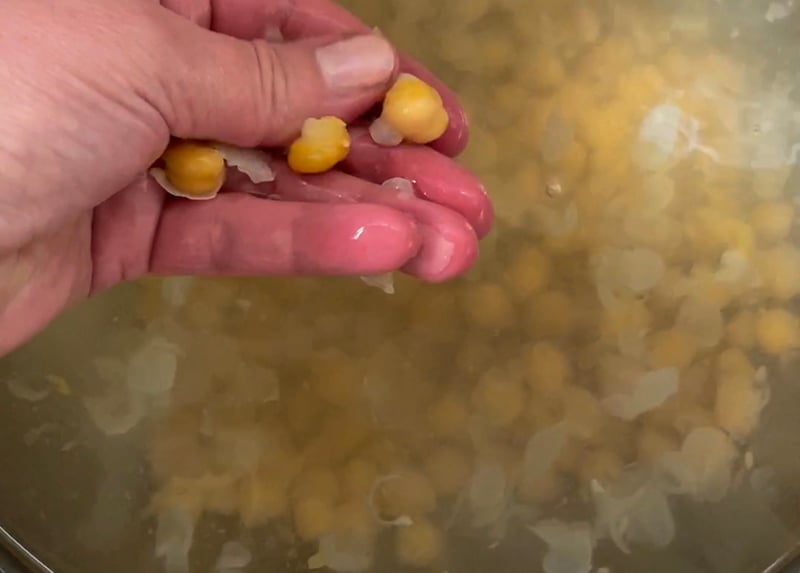 Removing chickpea skins by hand in a bowl of water.