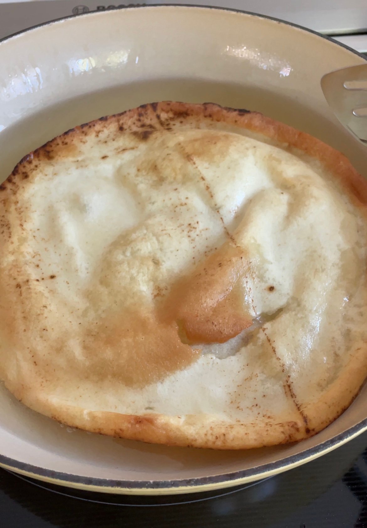 a loaf of pita bread in deep oil for frying in a pan