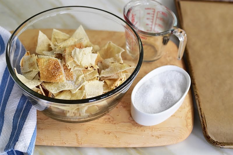 Pita pieces in a glass bowl with a small dish of salt next to it.