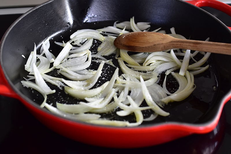 Sliced onion being cooked in a skillet.