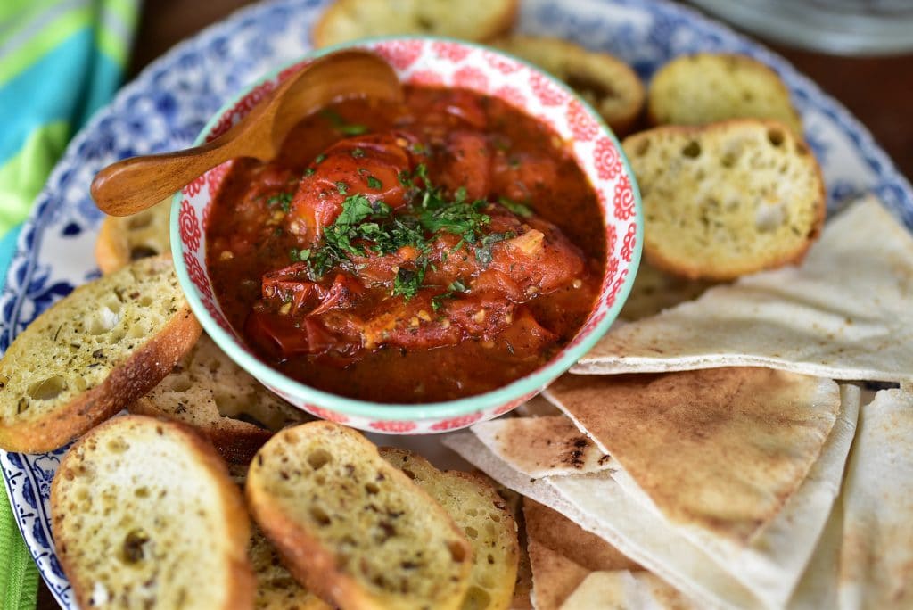 Lebanese salsa up close, in a bowl with a small spoon surrounded by bread for dipping