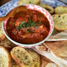 Lebanese salsa up close, in a bowl with a small spoon surrounded by bread for dipping