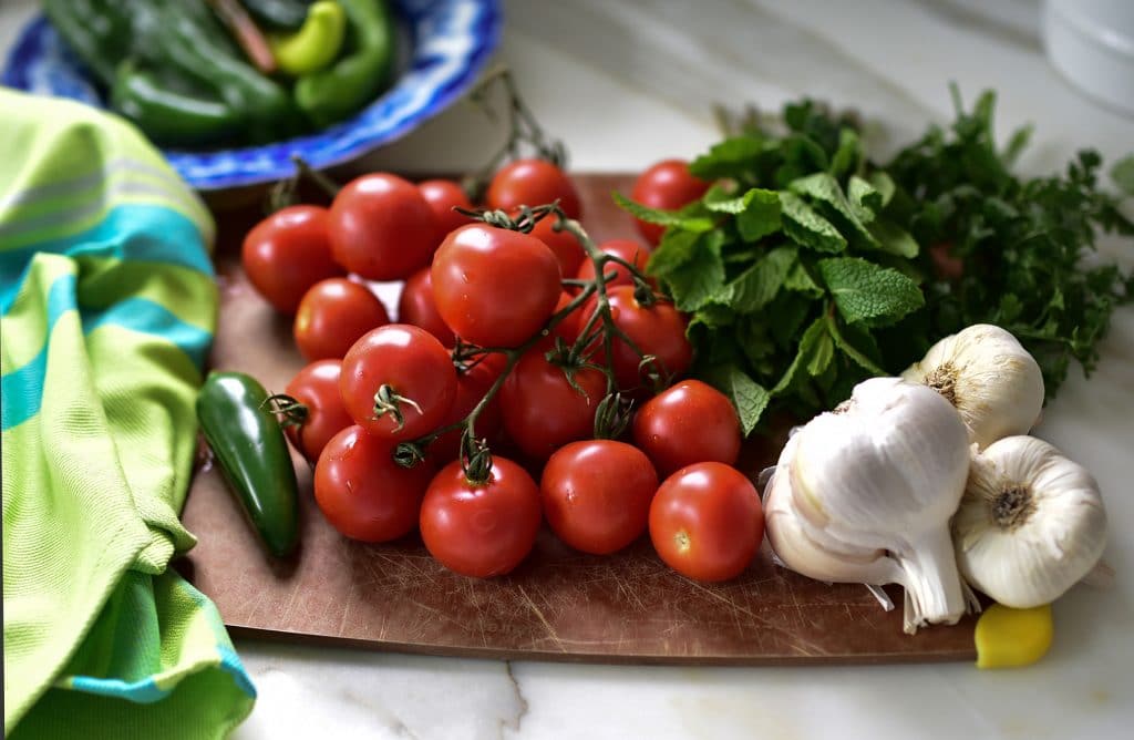 Tomatoes, mint, cilantro, garlic and chilis on a cutting board