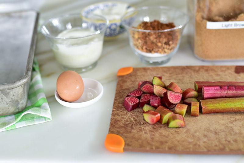 Ingredients for rhubarb cake, with yogurt, nuts, brown sugar, and rhubarb.