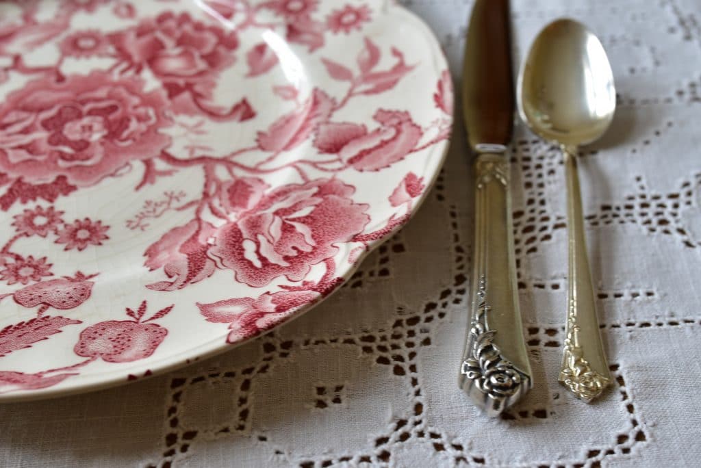Sterling silver with a rose pattern and rose chintz china plate on a cream hemstitched tablecloth