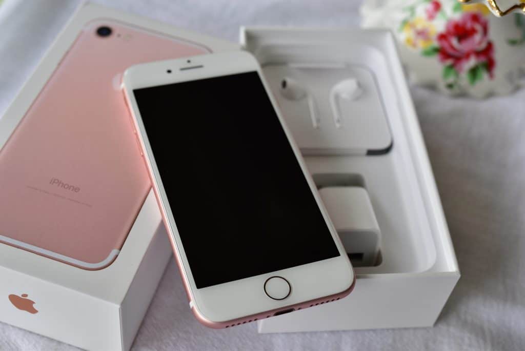 Rose colored iPhone with its box and earbuds
