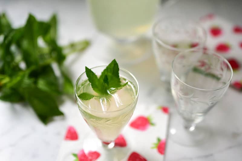 Fresh mint lemonade with fresh mint sprigs in small glasses on a strawberry printed napkin, Maureen Abood.com