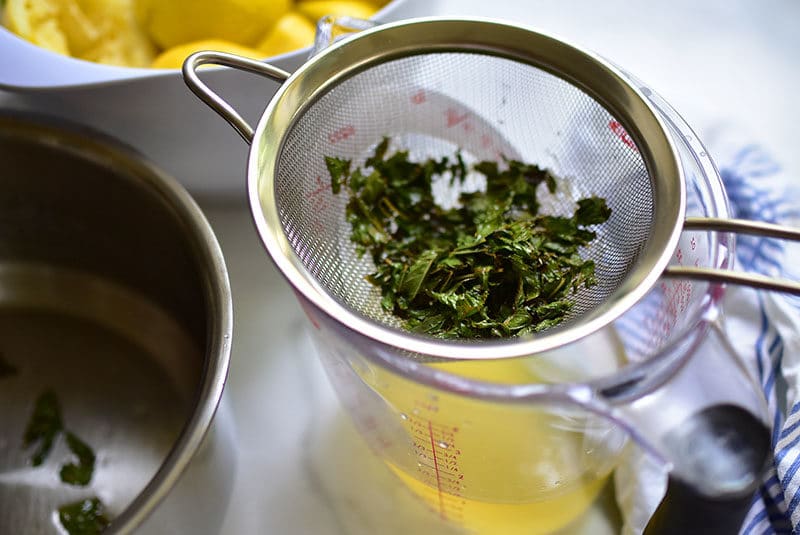 Fresh mint strained from lemon syrup for lemonade.