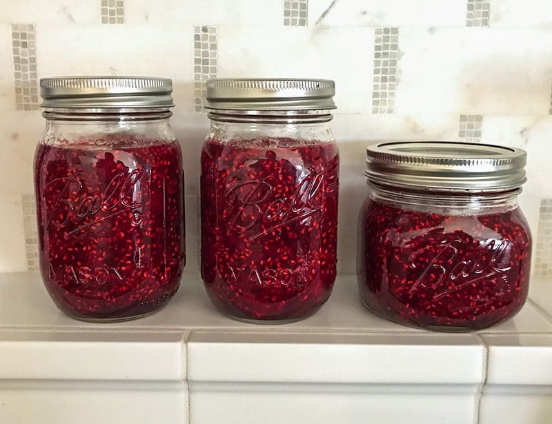Simple Raspberry Jam in Ball jars on a tile kitchen shelf, Maureen Abood