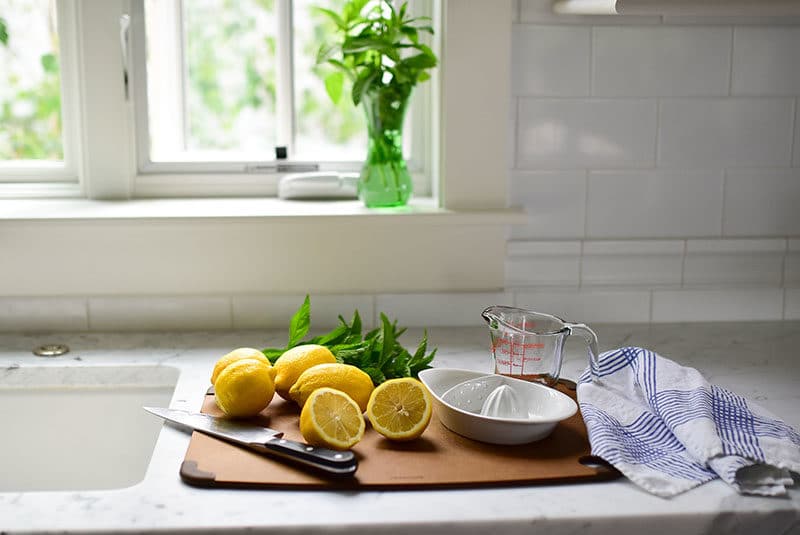 Lemons cut for juicing on a board with a knife and towel underneath the window, Maureen Abood.com