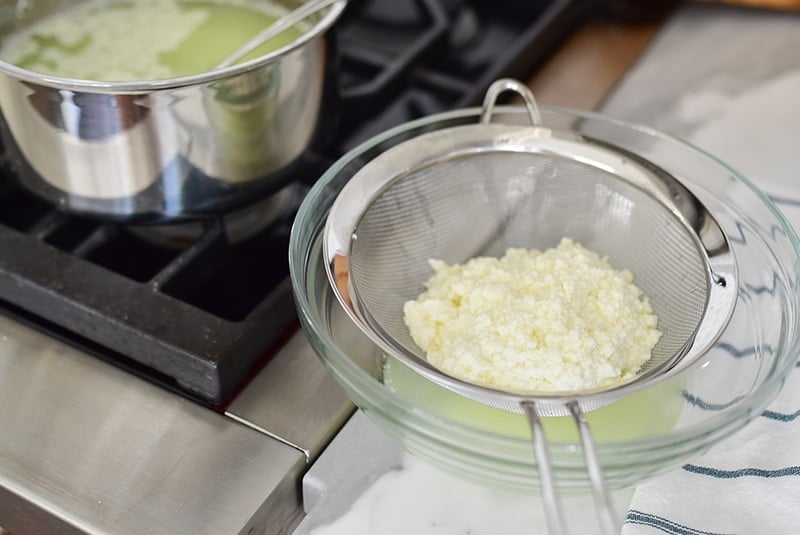 Clotted cream in einem Sieb für das Ashta-Rezept, mit Topf mit kochender Milch daneben, Maureen Abood