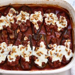 Lebanese eggplant boats in tomato sauce topped with cheese and pine nuts, in a white casserole