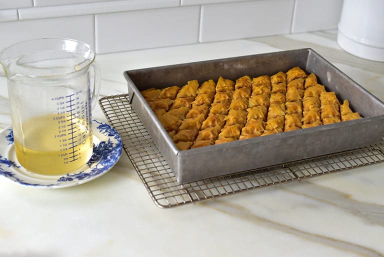 Simple Syrup in a pitcher next to a pan of golden Lebanese Baklawa