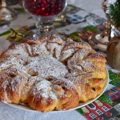 Brioche star with strawberry rose jam topped with powdered sugar on a round platter