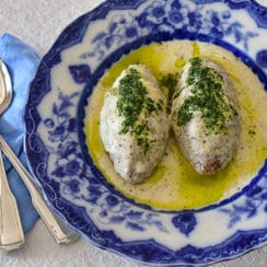 Kibbeh balls with yogurt sauce topped with olive oil and herbs in a blue dish